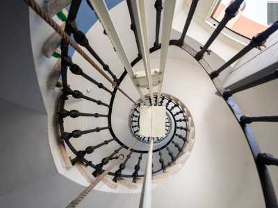 Alziamo lo sguardo restando incantati dalla visuale a spirale della rampa di scale che circonda un meccanismo a corda che corre lungo tutta la colonna centrale